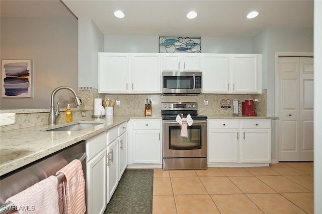 kitchen featuring tasteful backsplash, sink, light tile patterned flooring, appliances with stainless steel finishes, and white cabinets