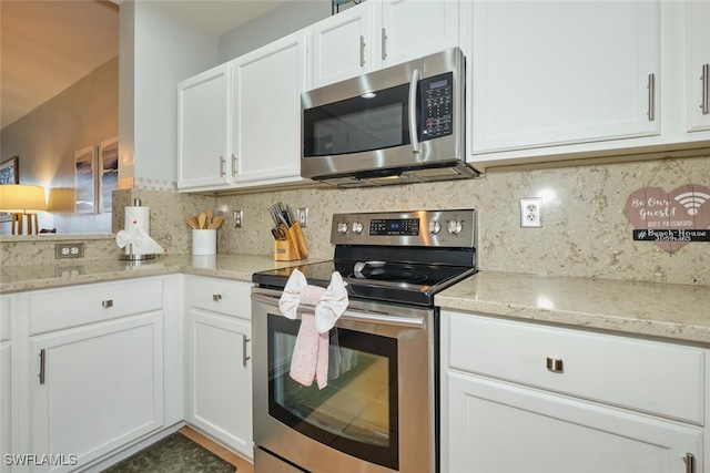 kitchen featuring backsplash, light stone counters, stainless steel appliances, and white cabinetry