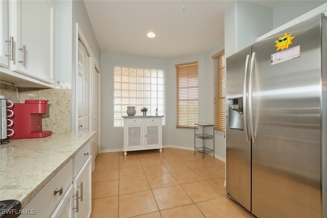 kitchen featuring stainless steel fridge with ice dispenser, light tile patterned flooring, white cabinets, and tasteful backsplash