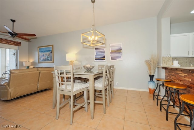 tiled dining space with ceiling fan with notable chandelier