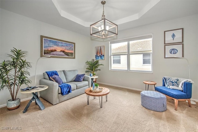 carpeted living room featuring a tray ceiling and a chandelier