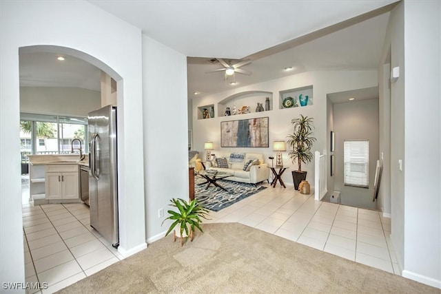 corridor featuring lofted ceiling, sink, and light tile patterned flooring