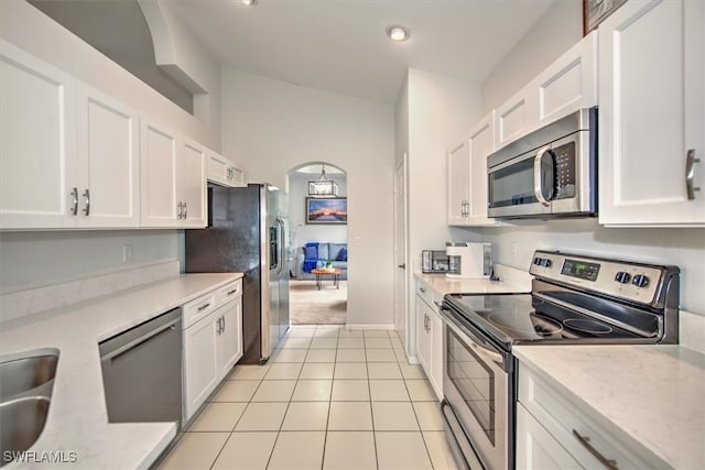 kitchen with light tile patterned floors, light stone counters, stainless steel appliances, and white cabinetry