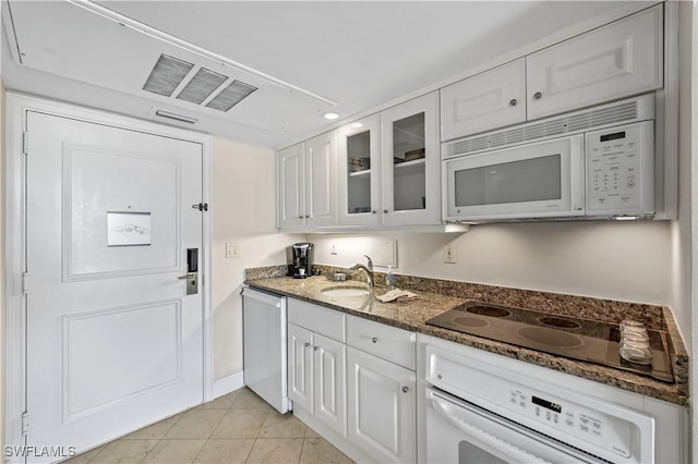 kitchen featuring sink, white appliances, white cabinets, and dark stone counters