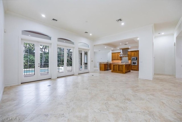 unfurnished living room with ornamental molding and french doors