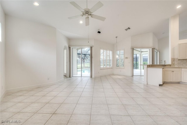 interior space with ceiling fan, sink, light tile patterned floors, and a wealth of natural light