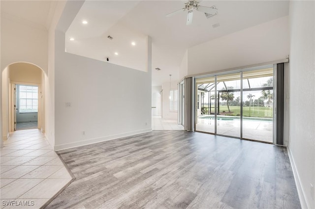 spare room featuring light wood-type flooring, ceiling fan, and a high ceiling