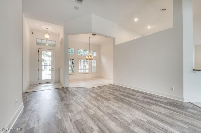 interior space with a high ceiling, an inviting chandelier, and light hardwood / wood-style floors