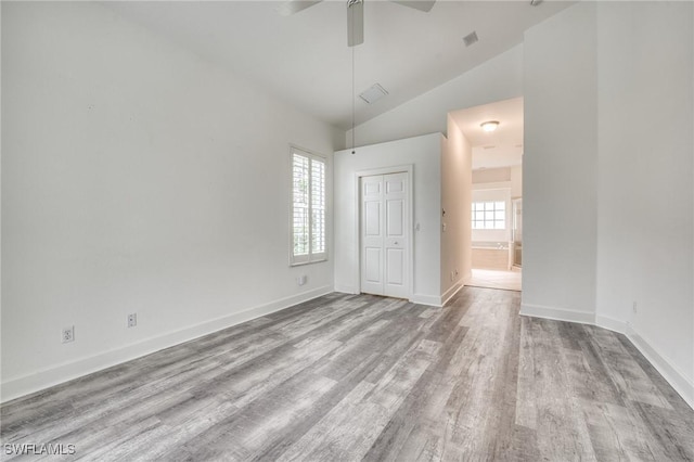 unfurnished bedroom featuring multiple windows, high vaulted ceiling, light hardwood / wood-style floors, and a closet