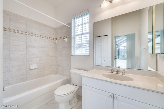 full bathroom featuring tiled shower / bath, vanity, and toilet