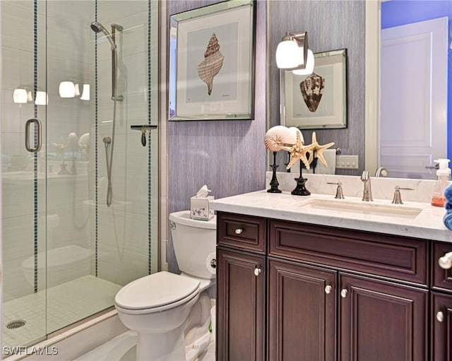 bathroom featuring vanity, toilet, and a shower with door