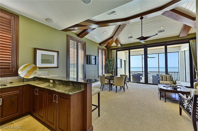 kitchen featuring a water view, dark stone counters, a kitchen breakfast bar, and kitchen peninsula