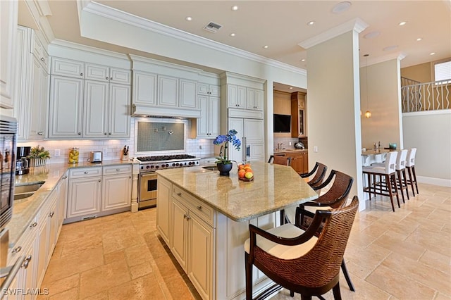 kitchen featuring a kitchen island, high quality appliances, a kitchen breakfast bar, crown molding, and light stone countertops