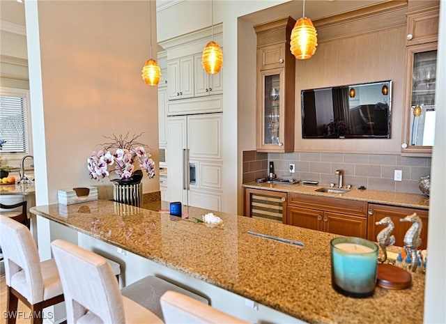 kitchen featuring light stone countertops, backsplash, a kitchen breakfast bar, and sink