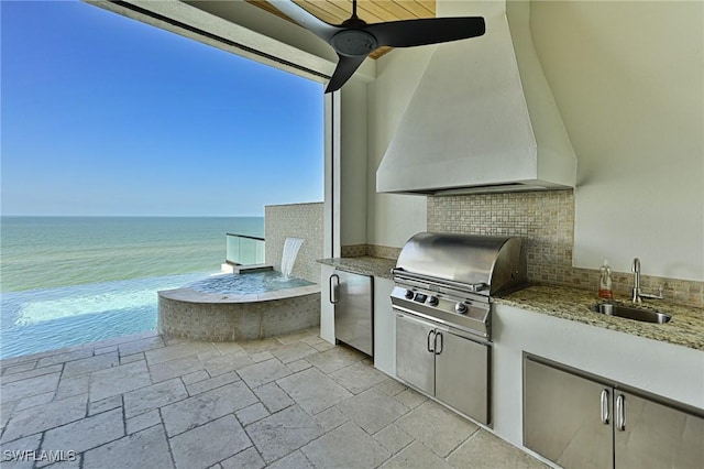 view of patio / terrace featuring sink, exterior kitchen, ceiling fan, grilling area, and a water view