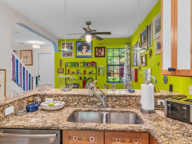 kitchen featuring ceiling fan, dishwasher, light stone counters, and sink