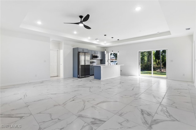 unfurnished living room featuring ceiling fan, a raised ceiling, and sink