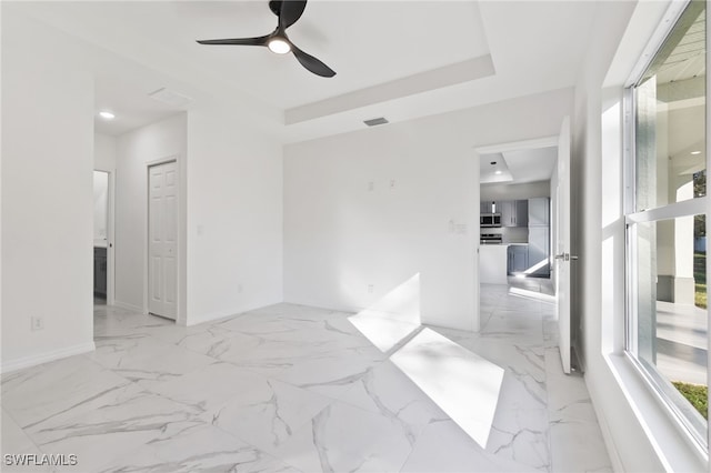 unfurnished room featuring ceiling fan and a tray ceiling