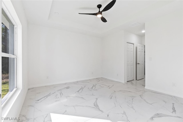 spare room with ceiling fan and a tray ceiling