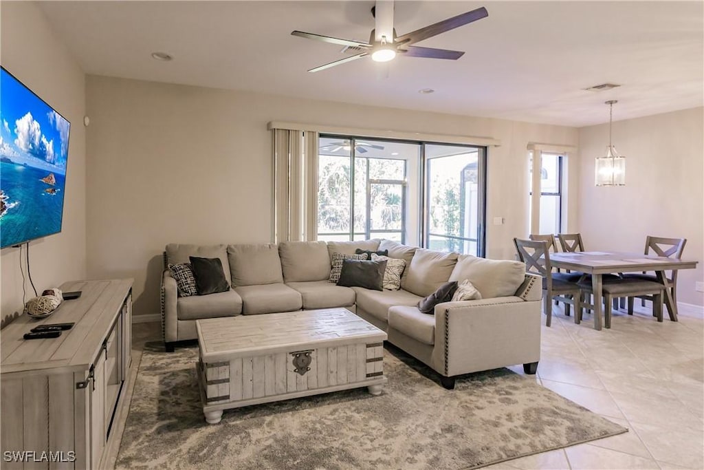 tiled living room featuring ceiling fan with notable chandelier