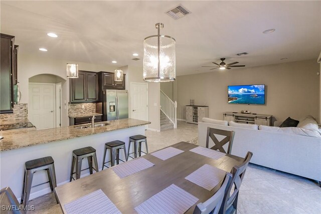 dining area with sink, ceiling fan with notable chandelier, and light tile patterned flooring