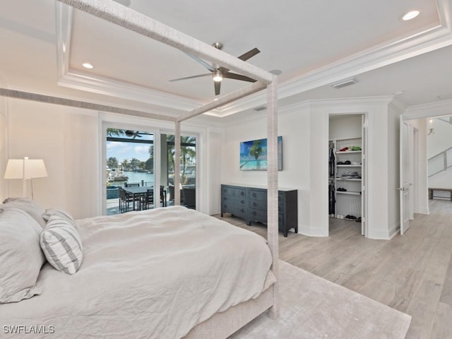 bedroom featuring crown molding, a walk in closet, access to exterior, a raised ceiling, and ceiling fan