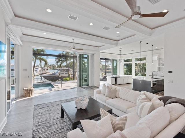 living room featuring beamed ceiling, hardwood / wood-style floors, sink, ornamental molding, and ceiling fan