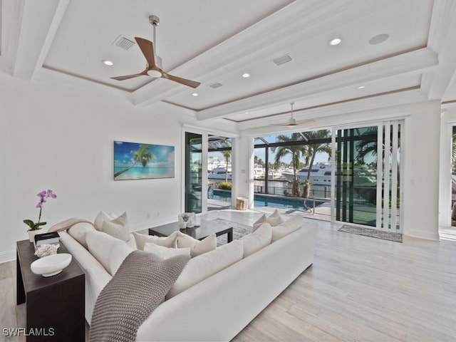 living room featuring ceiling fan, a tray ceiling, beamed ceiling, and light wood-type flooring