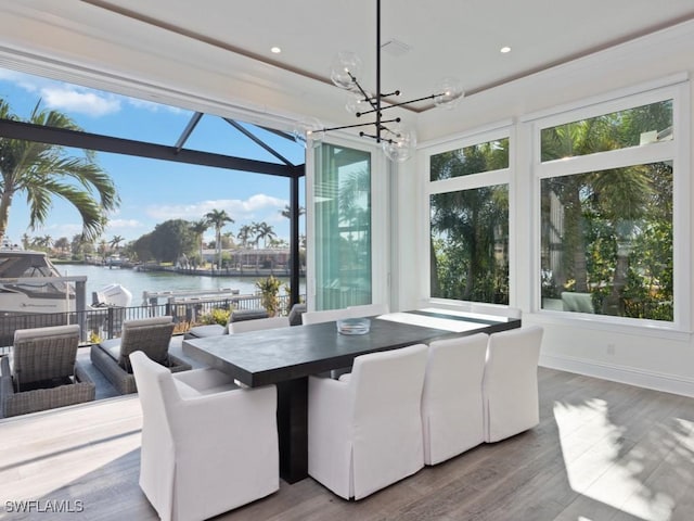 dining area with a notable chandelier, a water view, plenty of natural light, and wood-type flooring