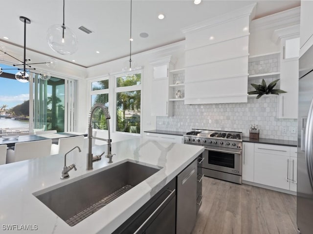 kitchen featuring white cabinets, hanging light fixtures, appliances with stainless steel finishes, and sink