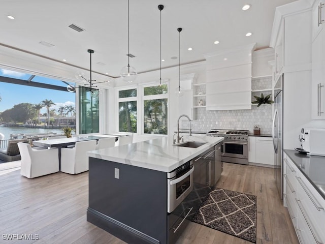 kitchen featuring sink, stainless steel appliances, a water view, and pendant lighting