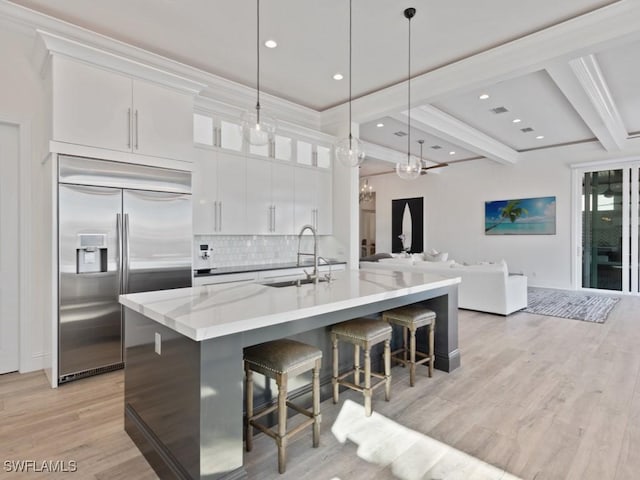 kitchen featuring sink, white cabinets, built in refrigerator, decorative backsplash, and beamed ceiling