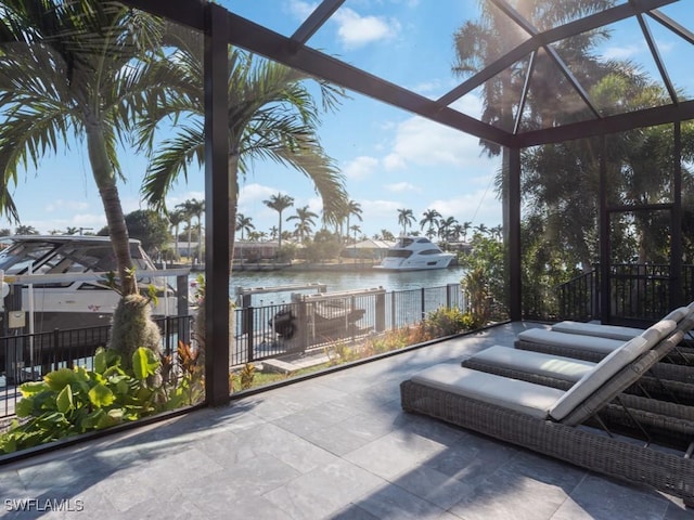 view of patio with a lanai and a water view