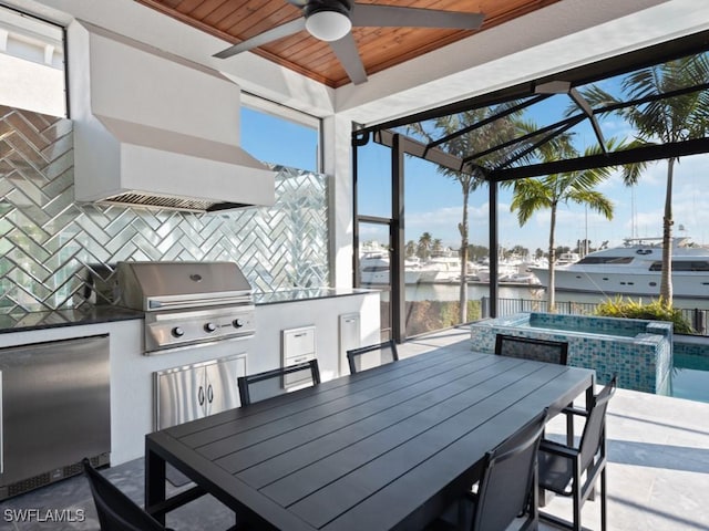 view of patio with exterior kitchen, area for grilling, and a water view