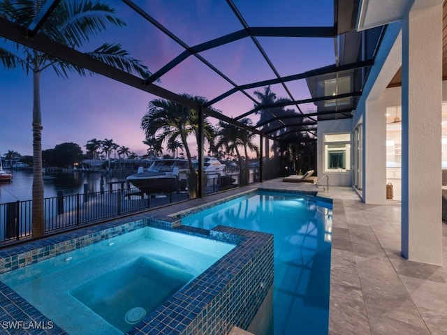 pool at dusk featuring an in ground hot tub, a lanai, a water view, and a patio