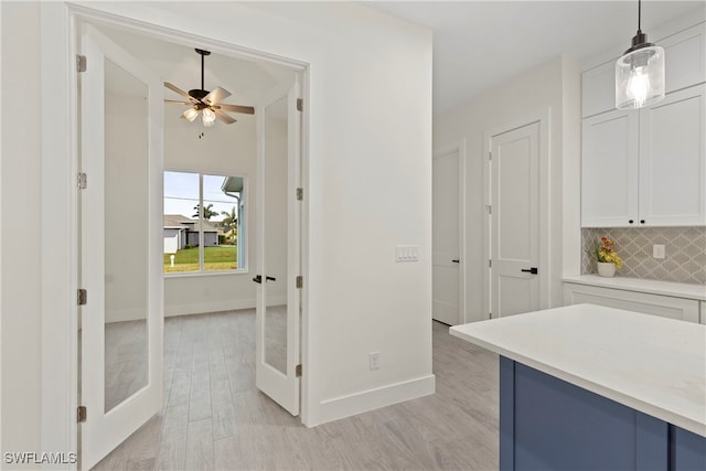 kitchen with light hardwood / wood-style flooring, hanging light fixtures, french doors, white cabinetry, and decorative backsplash