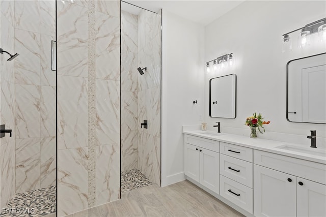 bathroom with hardwood / wood-style flooring, tiled shower, and vanity