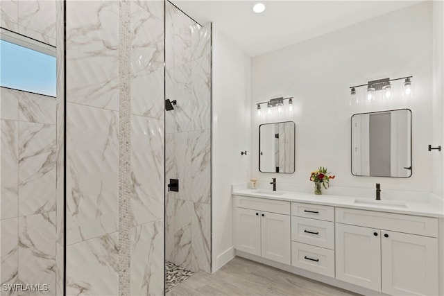 bathroom with wood-type flooring, vanity, and a tile shower