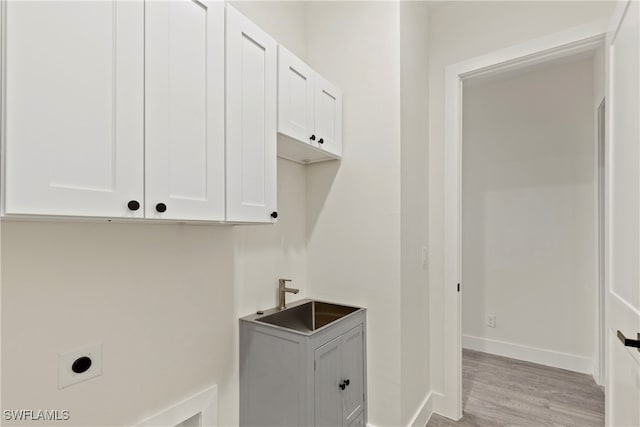 laundry room with cabinets, sink, hookup for an electric dryer, and light hardwood / wood-style floors