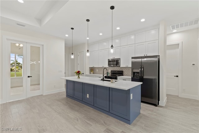 kitchen featuring white cabinets, hanging light fixtures, a center island with sink, and appliances with stainless steel finishes