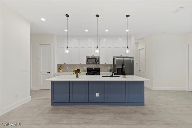 kitchen with decorative light fixtures, a center island with sink, white cabinetry, and stainless steel appliances