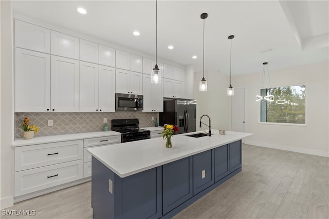 kitchen featuring decorative light fixtures, a center island with sink, and stainless steel appliances