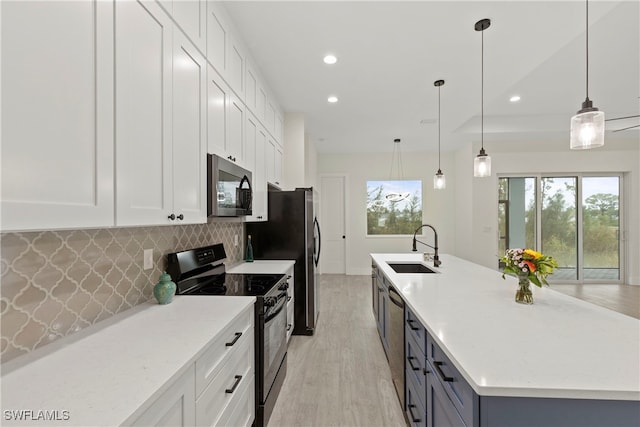 kitchen with decorative light fixtures, sink, white cabinetry, and appliances with stainless steel finishes