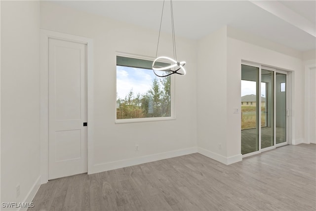 unfurnished dining area featuring a chandelier and light hardwood / wood-style flooring