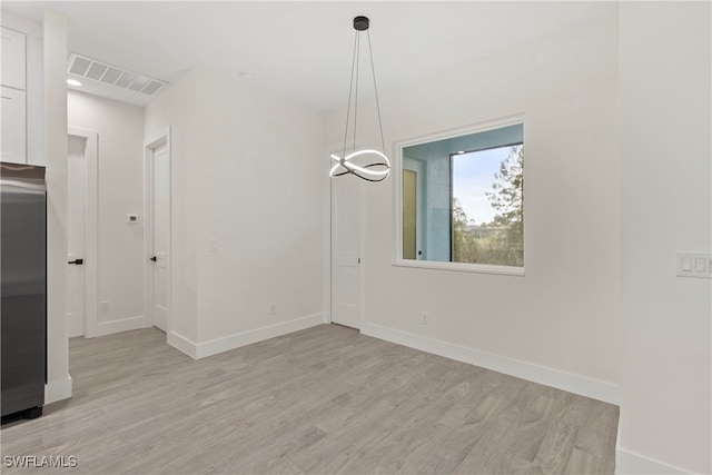 unfurnished room featuring an inviting chandelier and light hardwood / wood-style floors