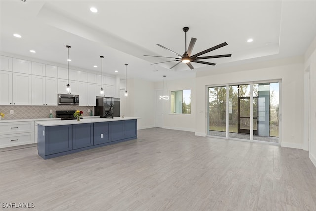 kitchen featuring hanging light fixtures, a large island, white cabinets, a tray ceiling, and stainless steel appliances