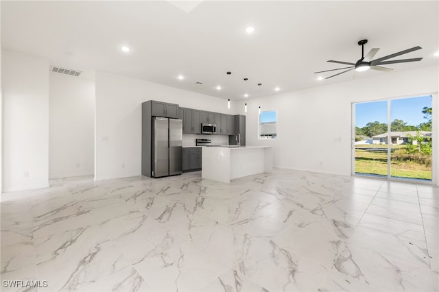 kitchen featuring pendant lighting, appliances with stainless steel finishes, a kitchen island, sink, and ceiling fan