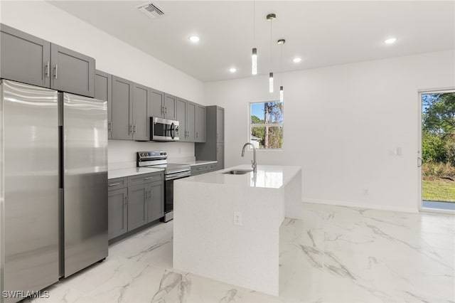 kitchen featuring visible vents, an island with sink, decorative light fixtures, stainless steel appliances, and light countertops