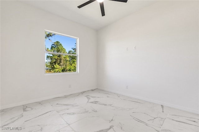 spare room featuring ceiling fan, marble finish floor, and baseboards