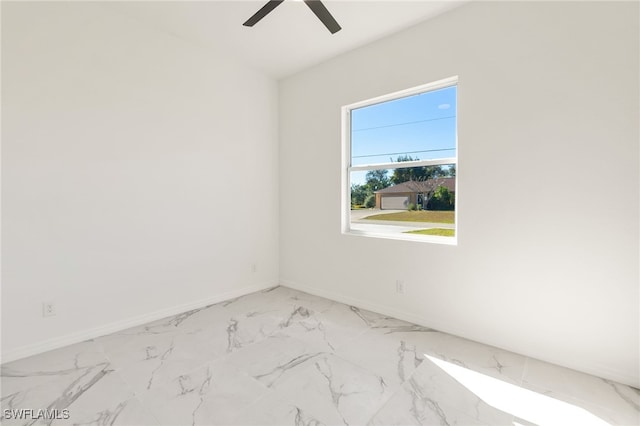 spare room featuring marble finish floor, a ceiling fan, and baseboards